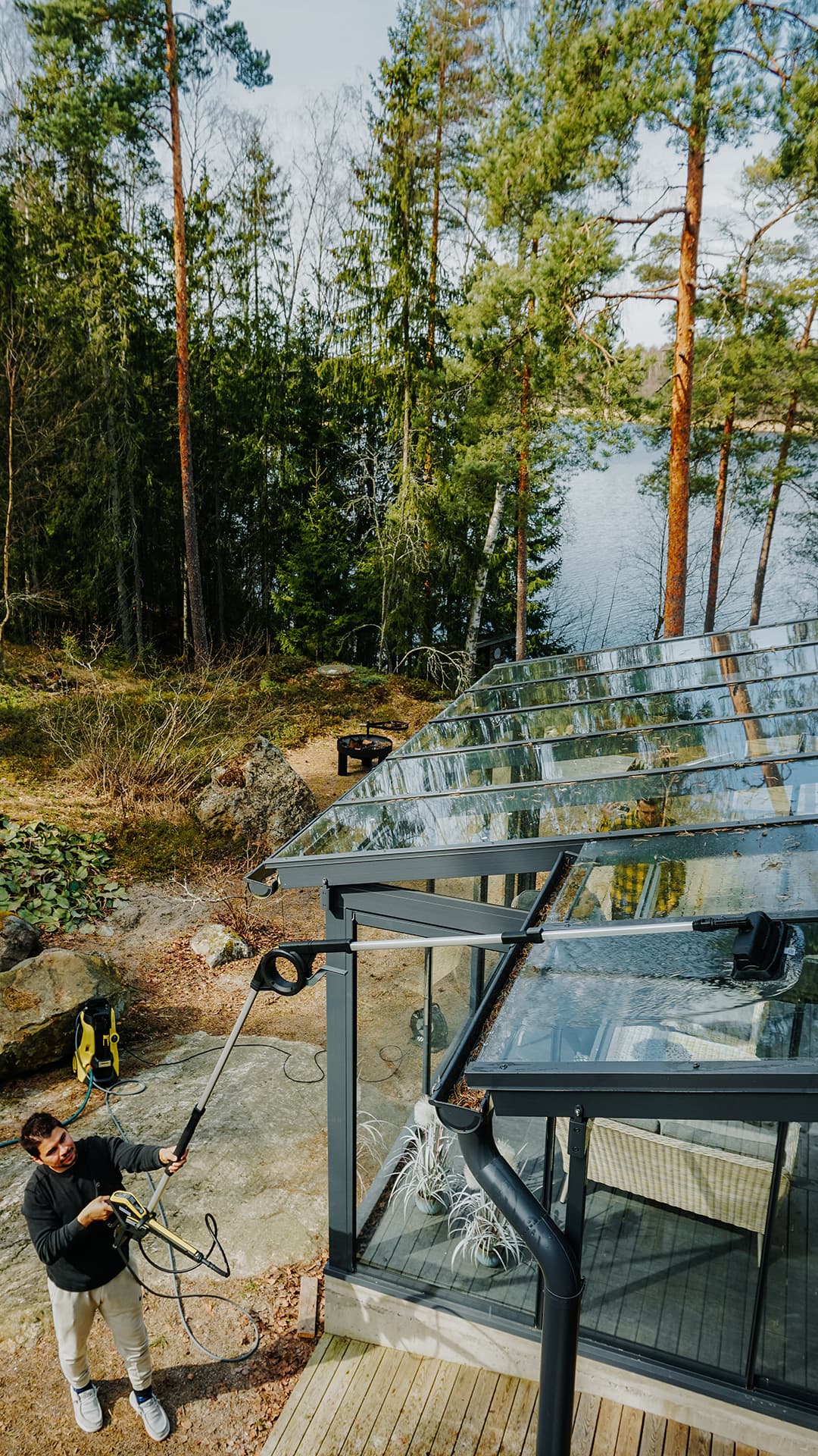 Mies pesee TLA 4 teleskooppivartta apuna käyttäen lasitetun terassin kattoa maasta käsin.