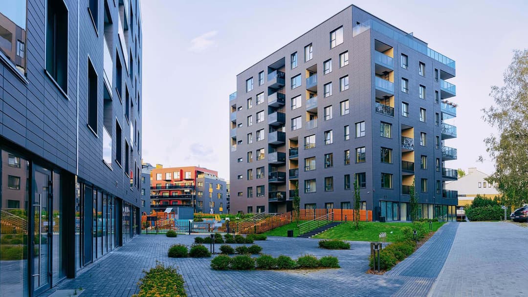 Tiiliverhoiltu kerrostalo kaupunkimaisemassa geonova