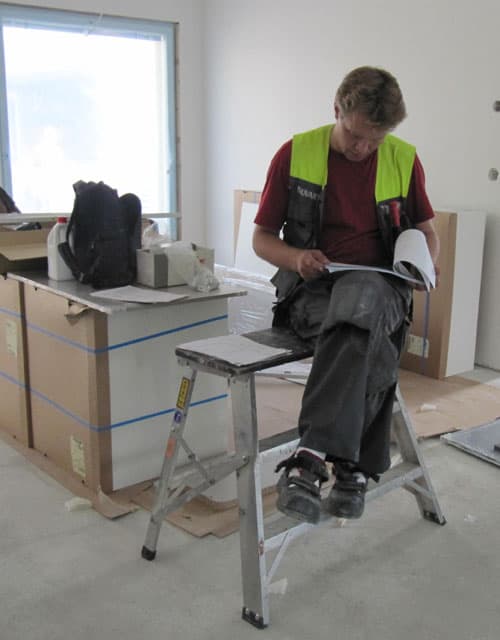 <p data-block-key="67um9">Tutkinnon suorittaja Ari Lehtinen selvittää piirustuksista yksityiskohdat ennen asennusta.</p>