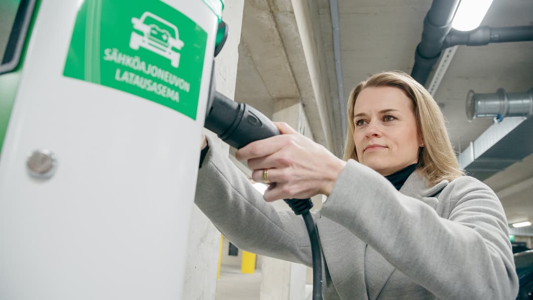nainen lataa sähköautoa