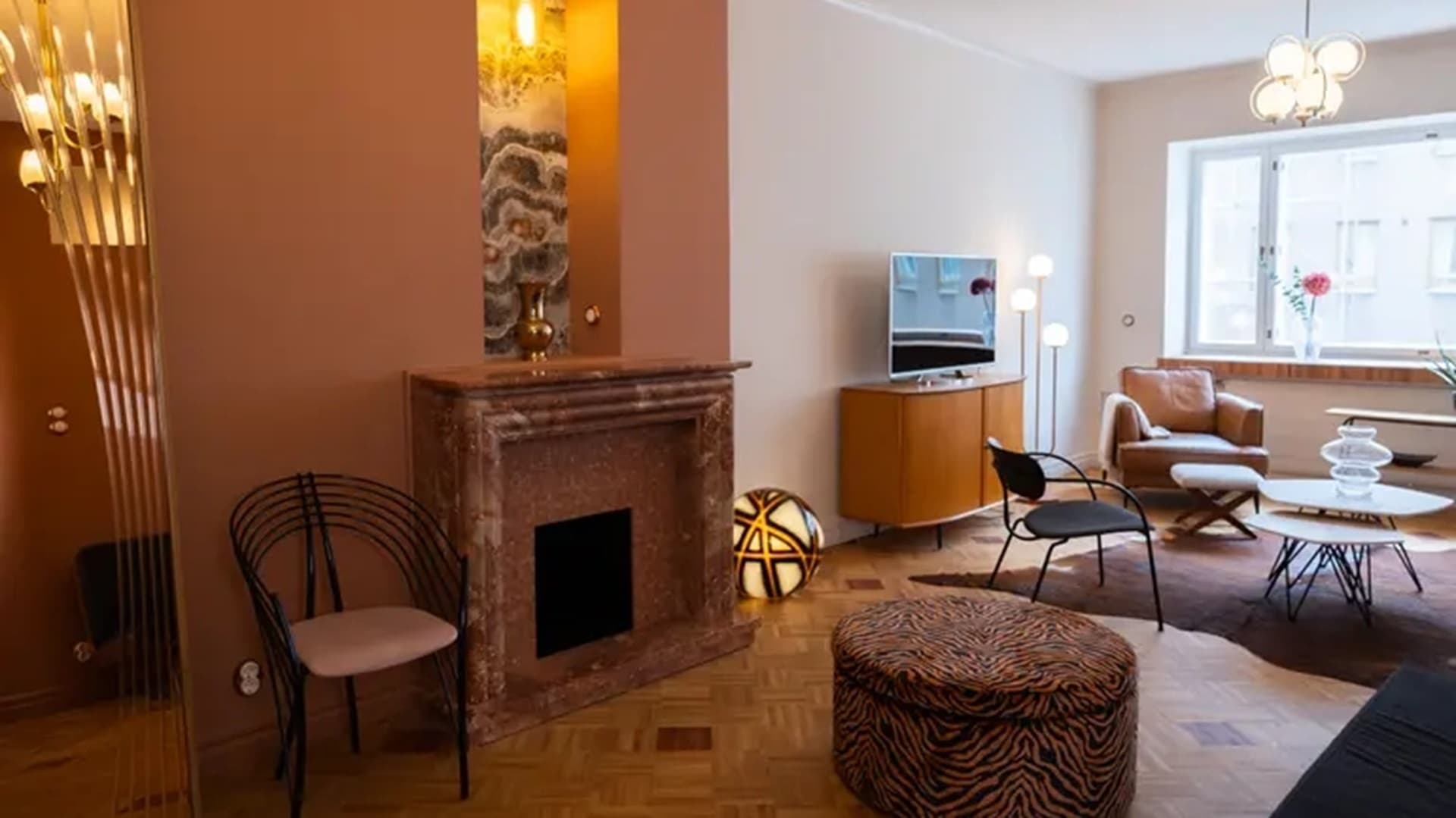 <p data-block-key="f2joo">Olohuoneen yhtenäinen mosaiikkiparketti ja punertava marmorinen takka luovat vahvan sisustuksellisen identiteetin.</p>