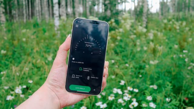 Puhelimen etäohjaus jonkun kädessä keskellä kesäistä metsää