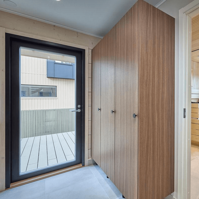 Kuvassa esiintyy lasiovi, joka luo tilantuntua ahtaaltakin tuntuvaan sivuoveen ja käytännölliset tummanruskeat kaapit todistaa käytännöllisyyttään. Harmaa laattalattia on edustavan ja käytännöllisen näköinen. Hi