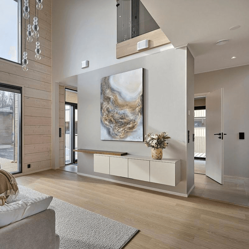 Kastellin hirsitalo oulun asuntomessuilta 2025. näyttävä taulu beigeseinää vasten tekee asunnosta näyttävän. ja järkyttävän korkea katto tekee asunnosta elegantin.