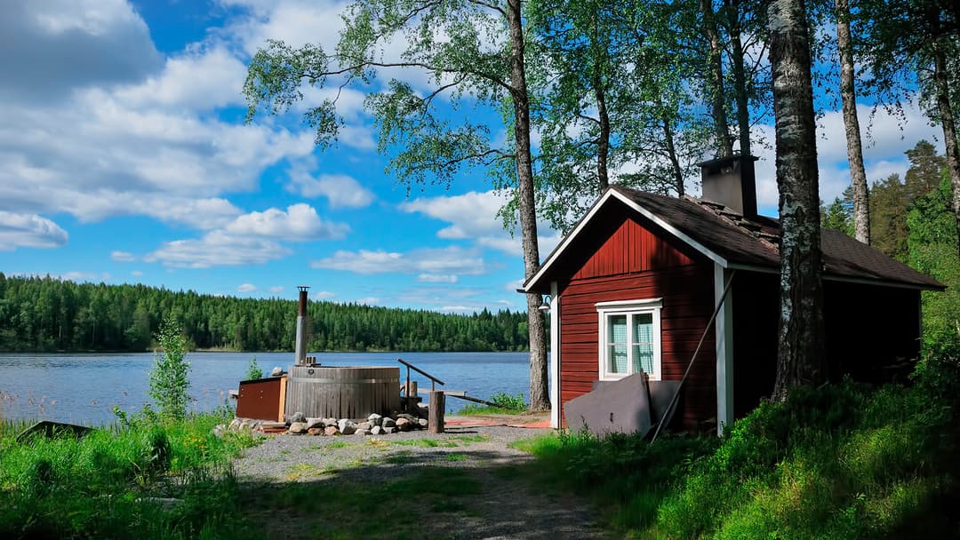 punainen saunamökki järven rannassa kesällä ja palju pihalla