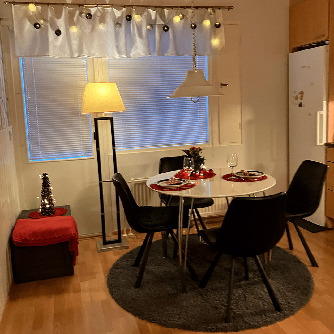 keittiön pöydän vieressä on 4 tuolia ja taustalla näkyy jääkaappi