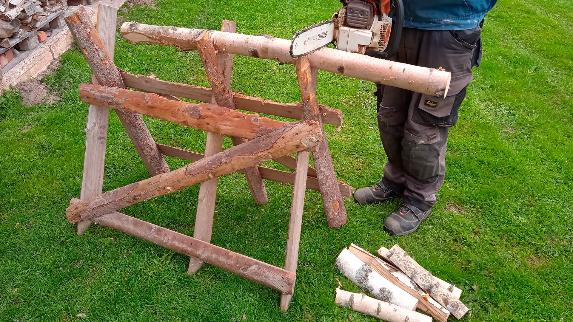 joku sahaa koivun runkoa sahapukin päällä moottorisahalla