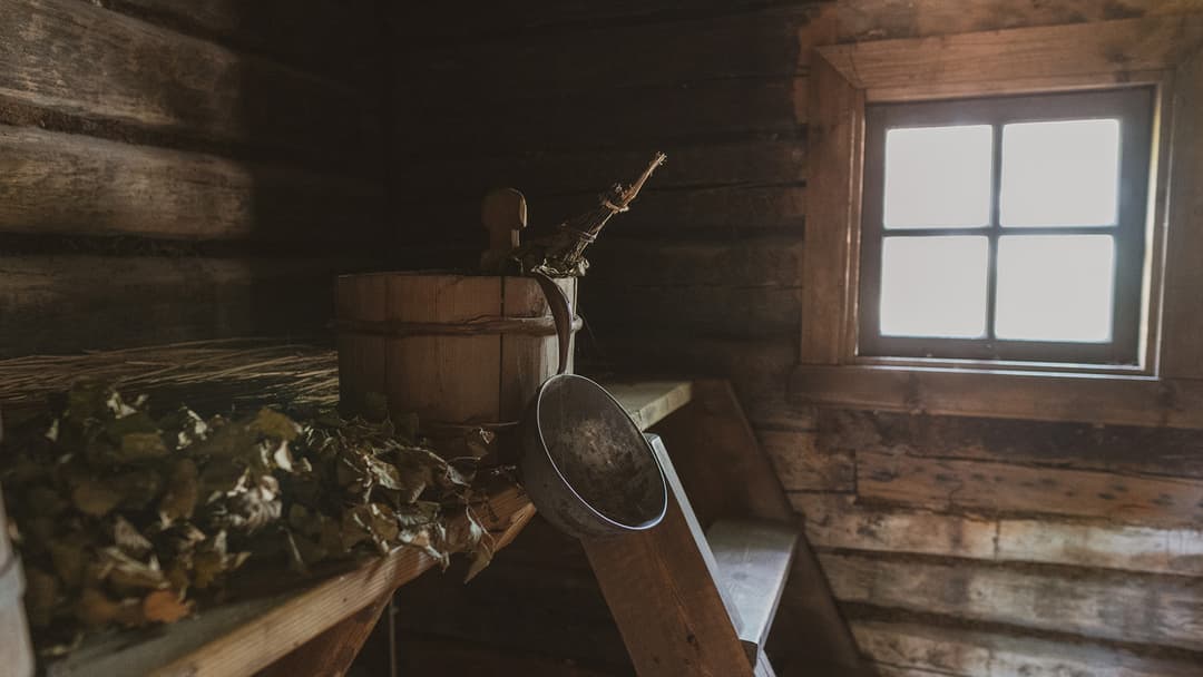 todella vanha ja tumma sauna. Saunassa on hirsiseinät, lauteilla puinen kiulu ja alumiininen kauha sekä vihta