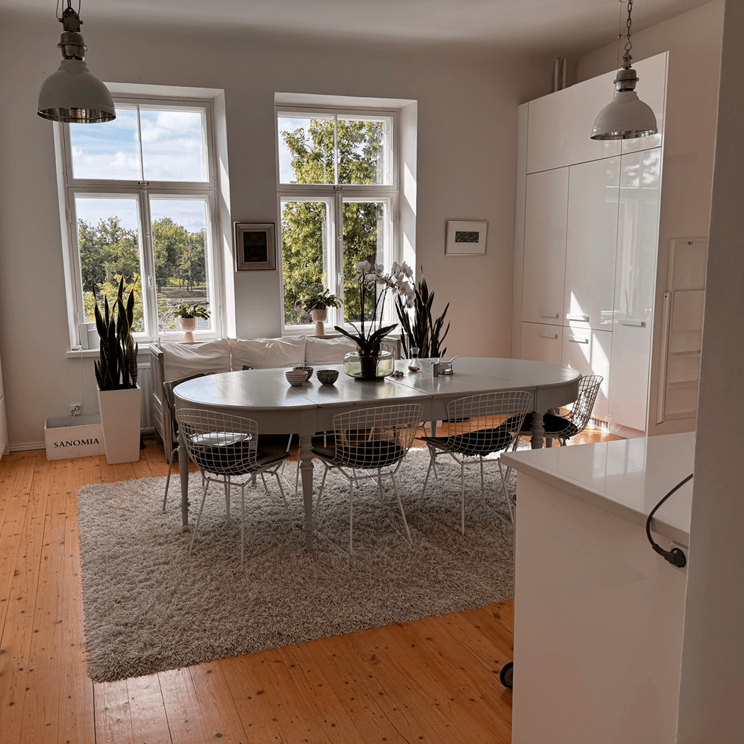 suuri keittiön pöytä keskellä lattiaa ja kaksi isoa ikkunaa avaa maiseman takana