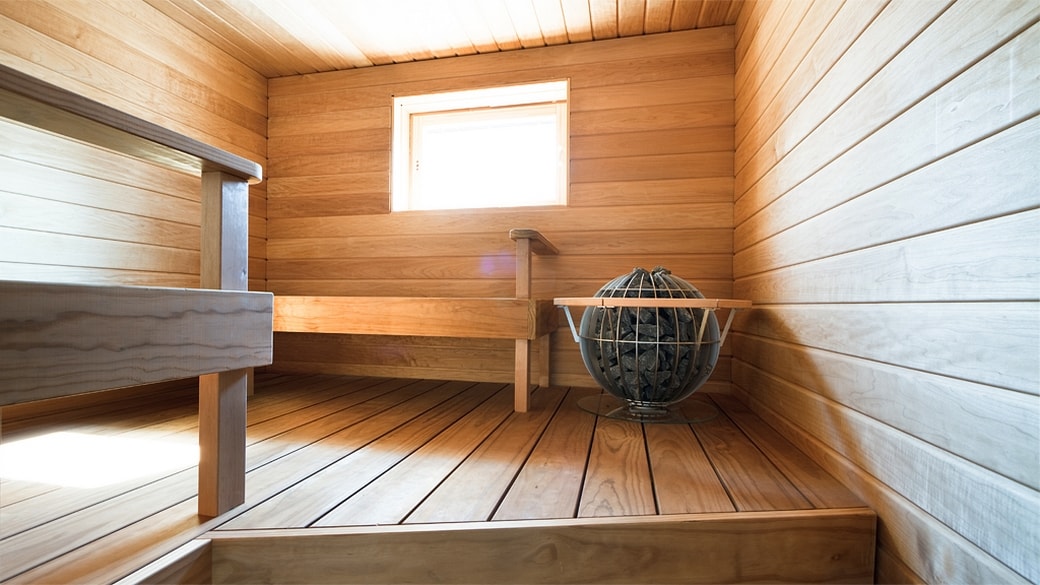 Paneloitu sauna, jonka nurkassa kiuas