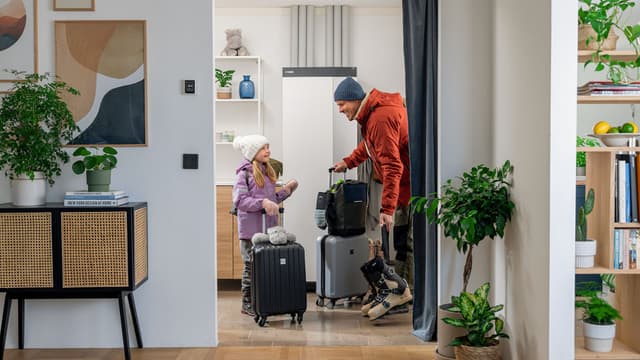 Perhe lähdössä matkalle taustalla NIBE lämpöpumppu