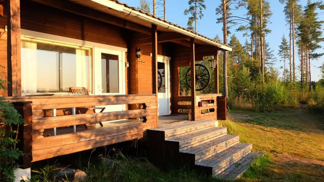 alhaalta paistava aurinko paistaa suoraan hirsirakenteiseen mökkiin taustalla männikköä