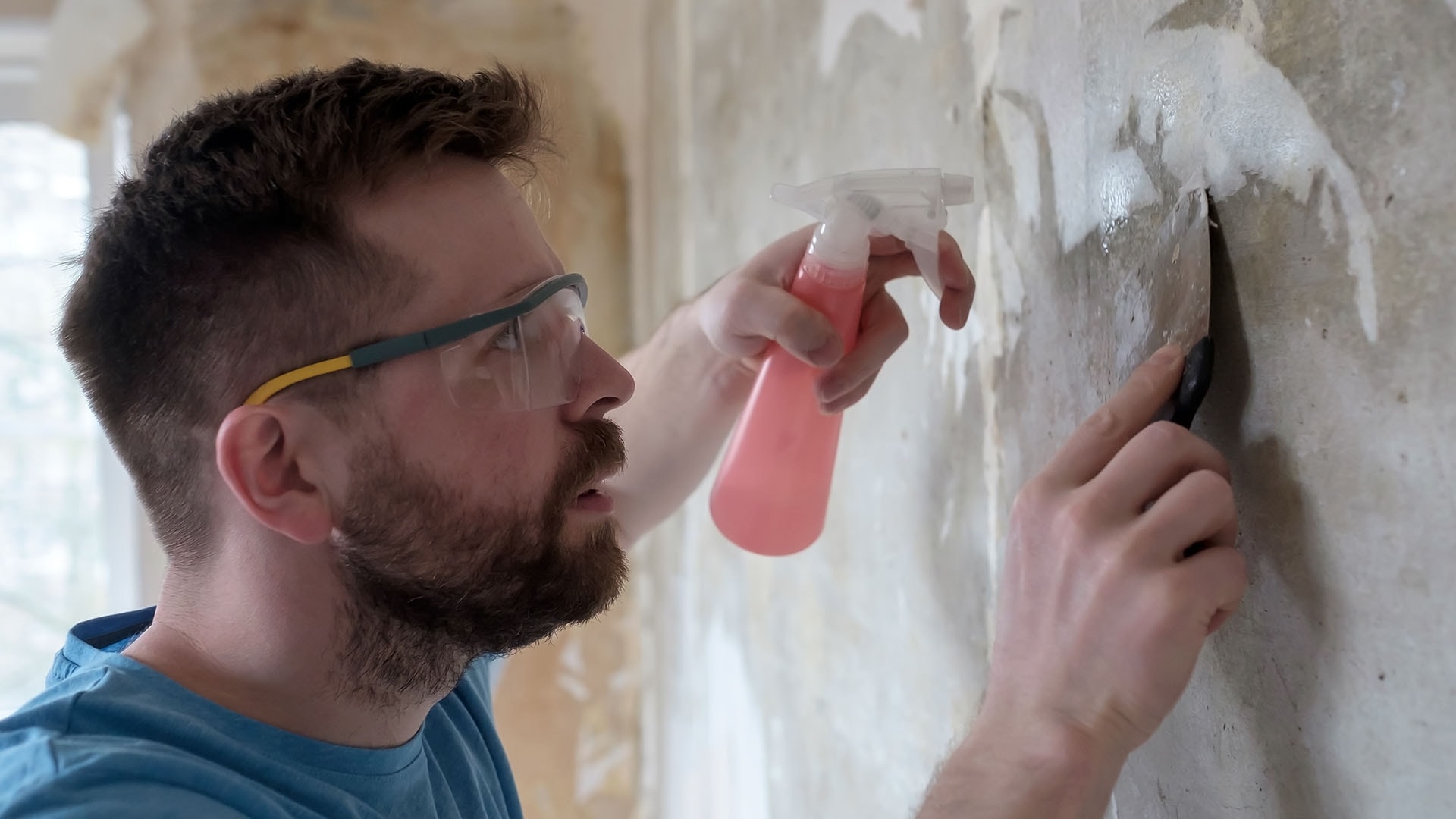 1920 home-repairs-focused-man-removes-old-wallpaper-fr-2023-11-27-05-18-09-utc