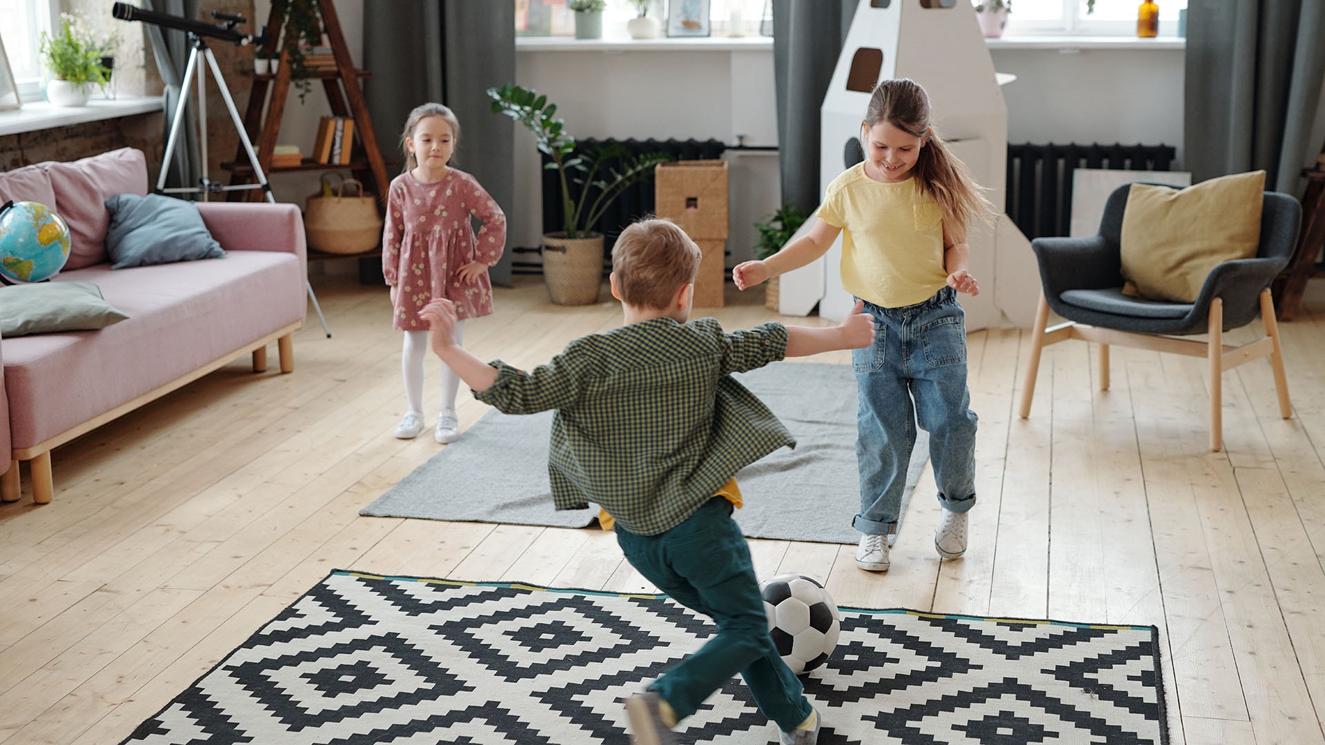 1920 iloiset lapset leikkivät sisällä olohuoneessa jalkapallolla