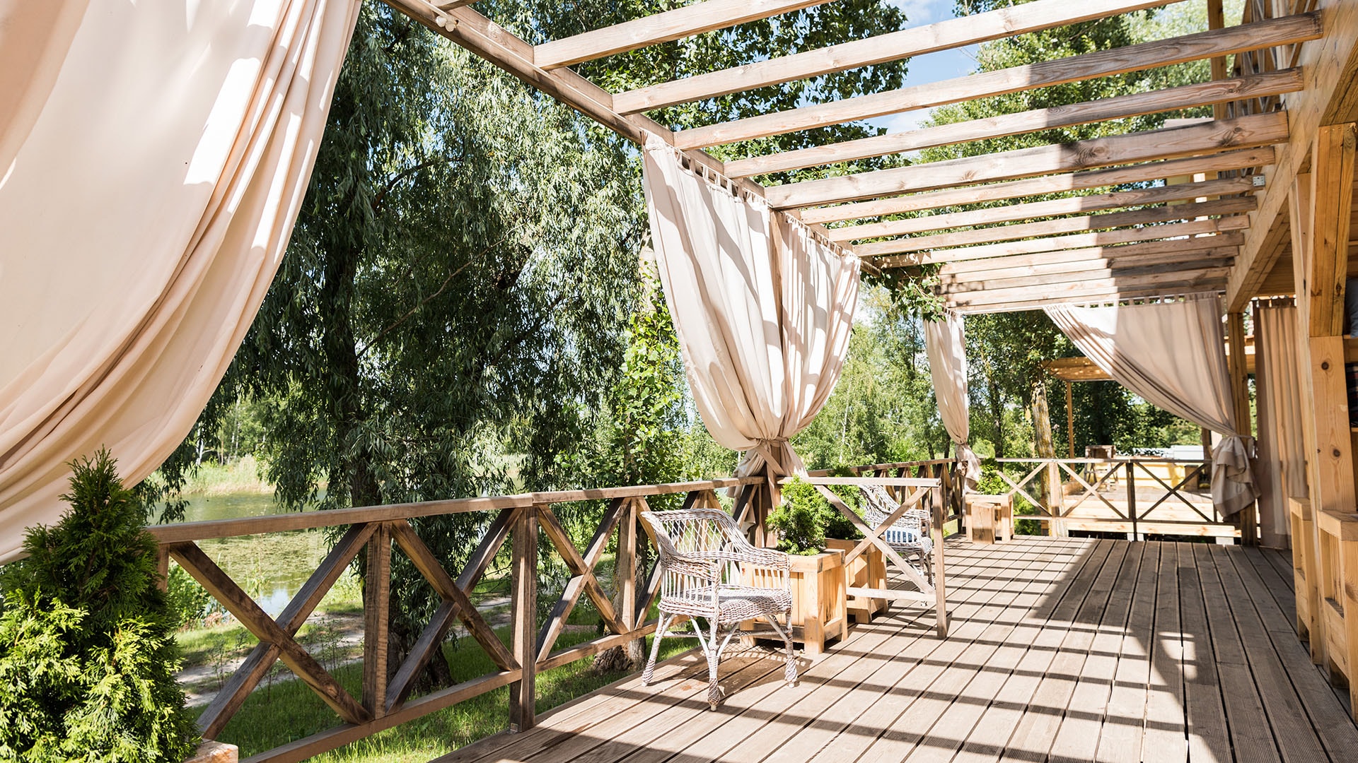 1920 kaunis ja kodikas puinen terassi jossa tyhjiä tuoleja ja pergola