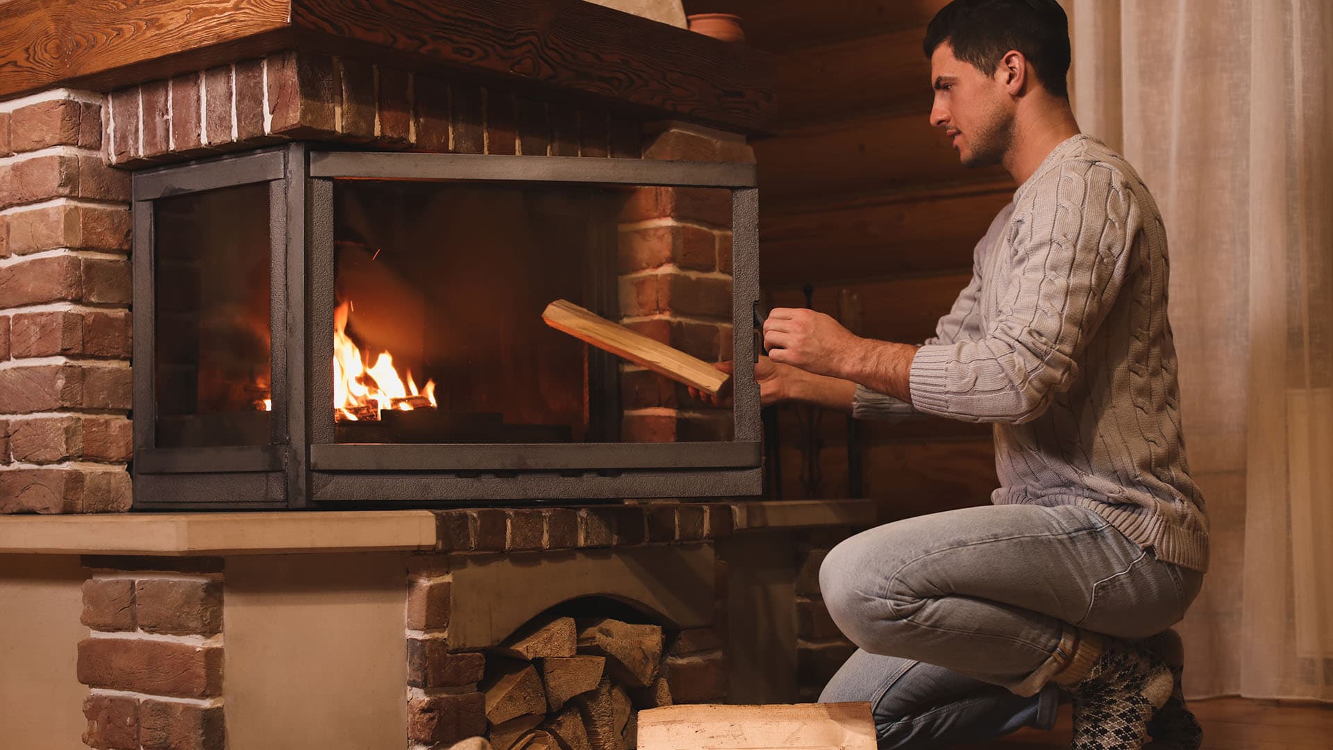mies latomassa puita ja sytyttämässä tulta takkaan