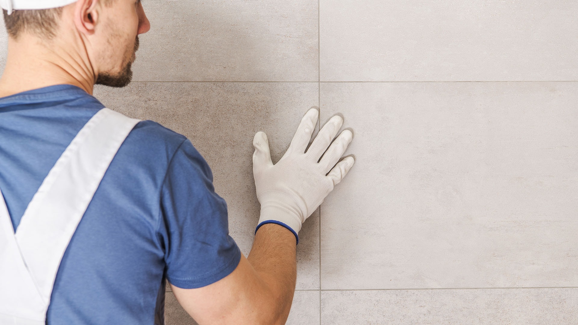 1920 mies sinisessä paidassa silittelee seinäpintaa keraamiset laatat asennettuna kylpyhuoneeseen