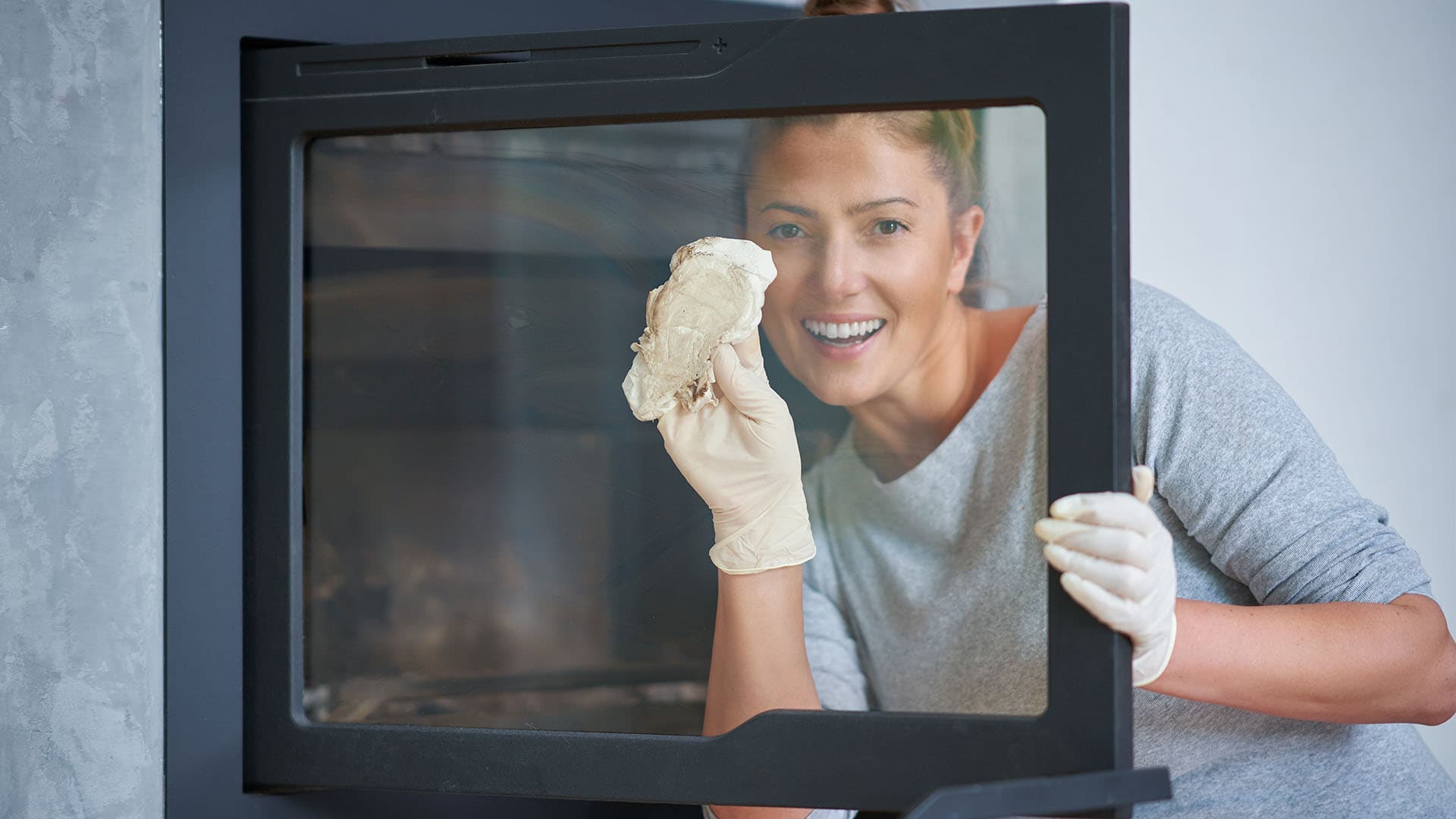 nainen puhdistaa takkaluukkua noesta