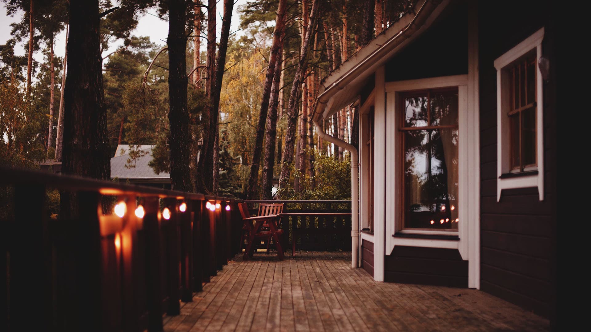 rustiikkinen mökin veranta iltahämärässä valoketjun valossa