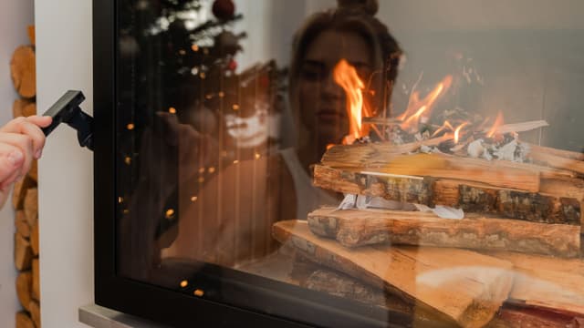 syttymässä oleva tulisija ja naisen heijastus luukusta