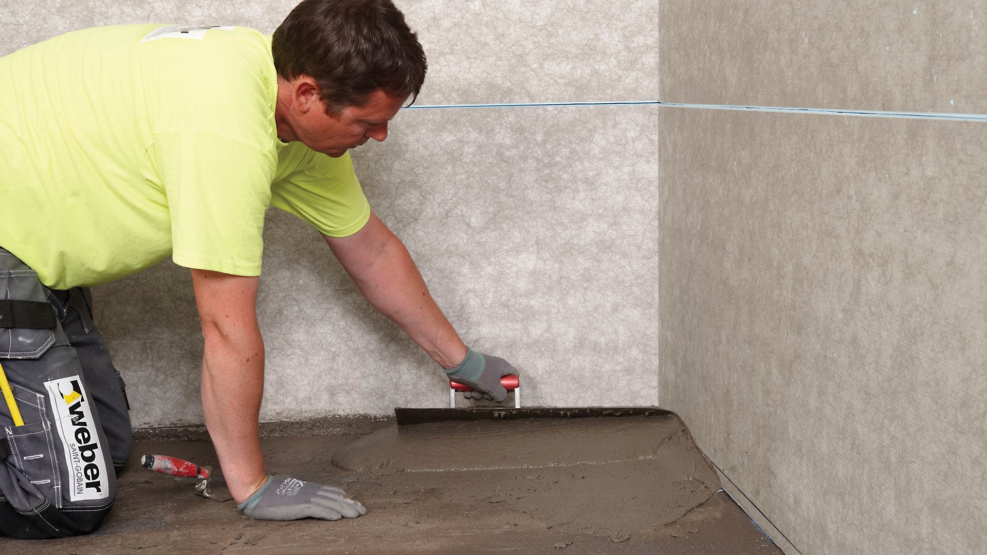 Mies tasoittaa lattiatasoitteen lastaa apuna käyttäen.