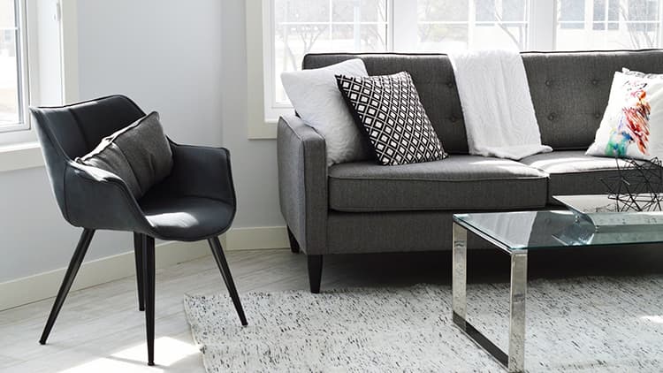 olohuoneen sisustus jossa harmaa sohva ja tumma nojatuoli
