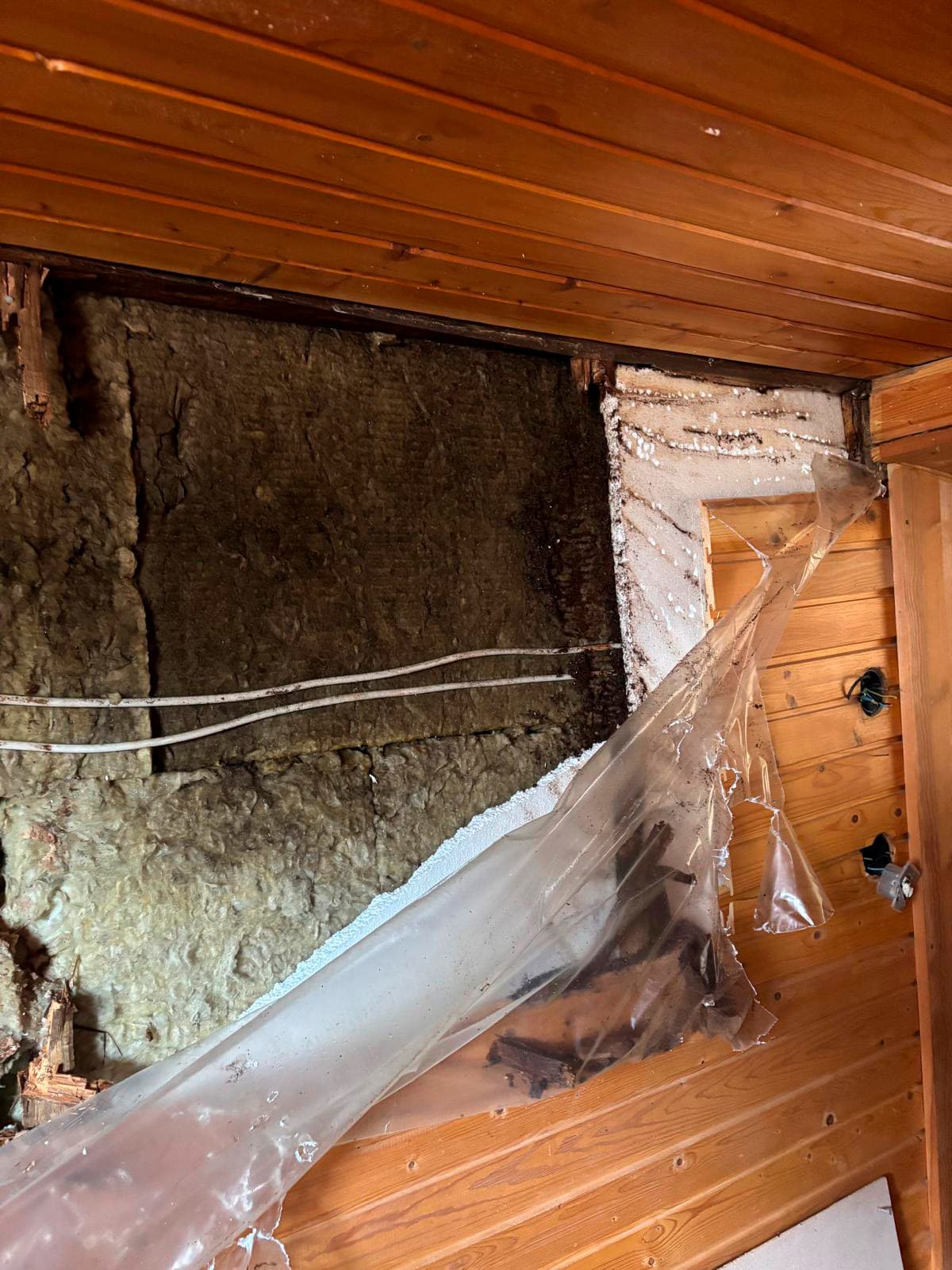 auki purettu hellarin paneeliseinä jossa tummuneet ja märät villat muovikalvojen välissä