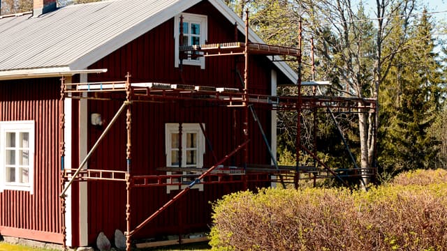 rakennustelineen mökin seinustalla remontin tekoa varten