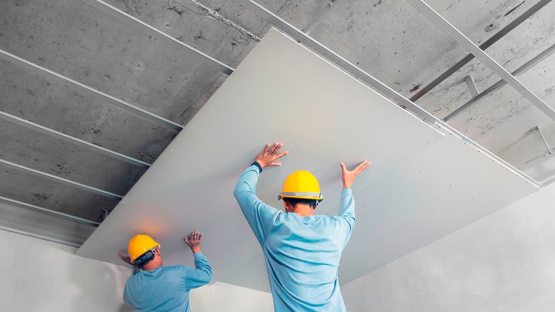 miehet nostavat kipsilevyä kattoon