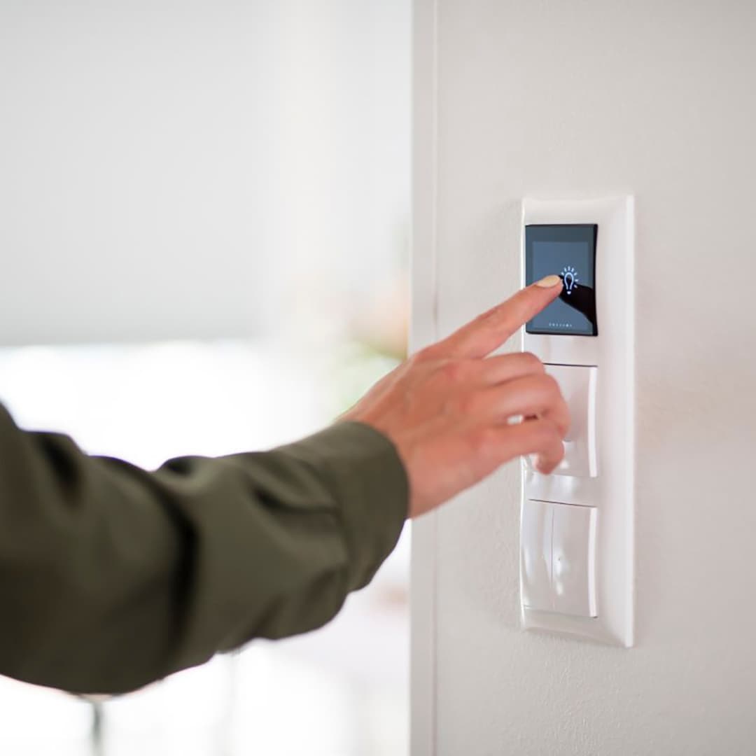 kuvassa näkyy käsi joka painaa valonsäädintä kotiautomaation hallintapanelista