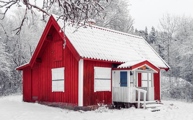 Punainen mökki lumisessa talvimaisemassa talvella.