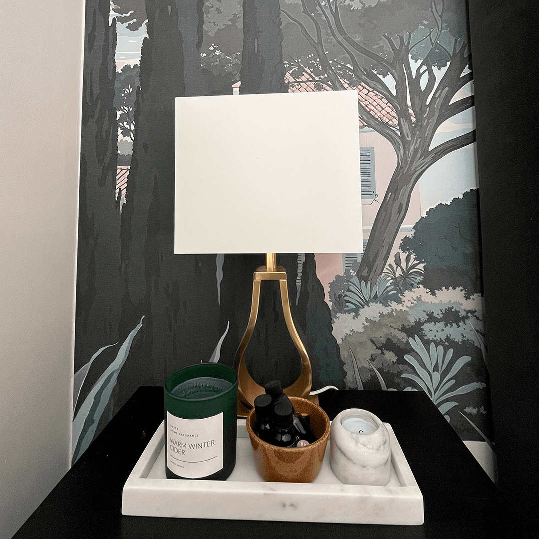 yöpöydällä neliön muotoinen lukuvalo ja taustalla toscana-tapetti