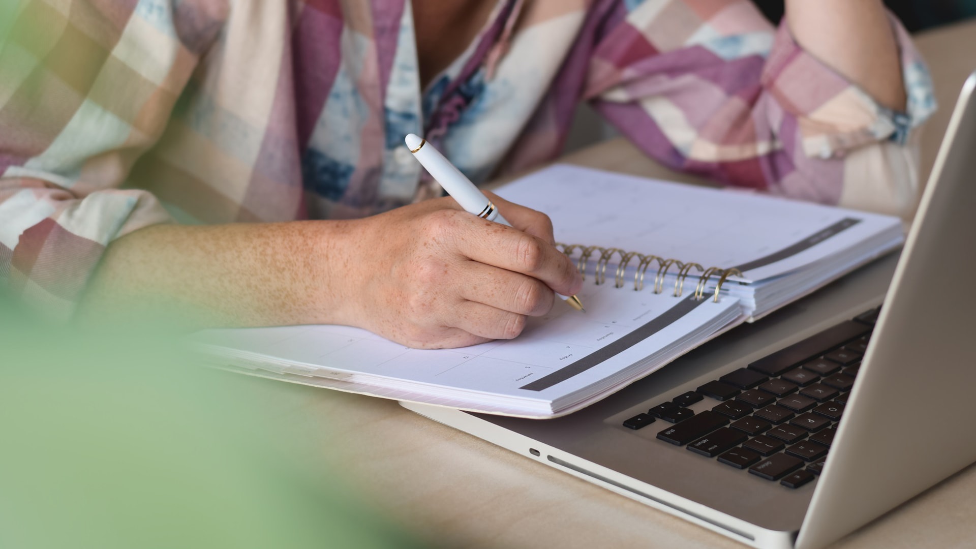 woman-sitting-at-desk-with-laptop-computer-and-wri-2023-11-27-05-19-12-utc