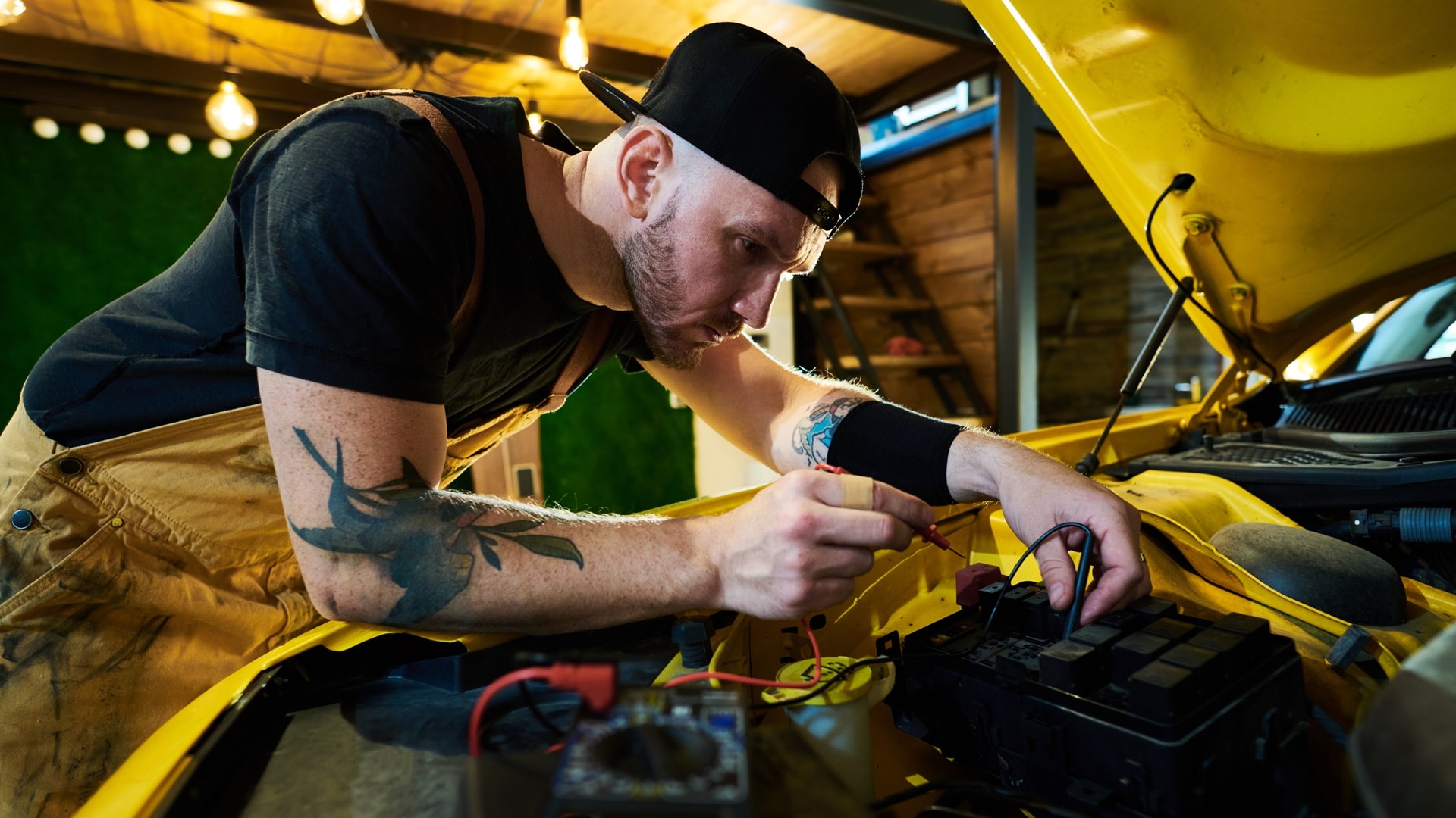 young-repairman-bending-over-open-hood-with-engine